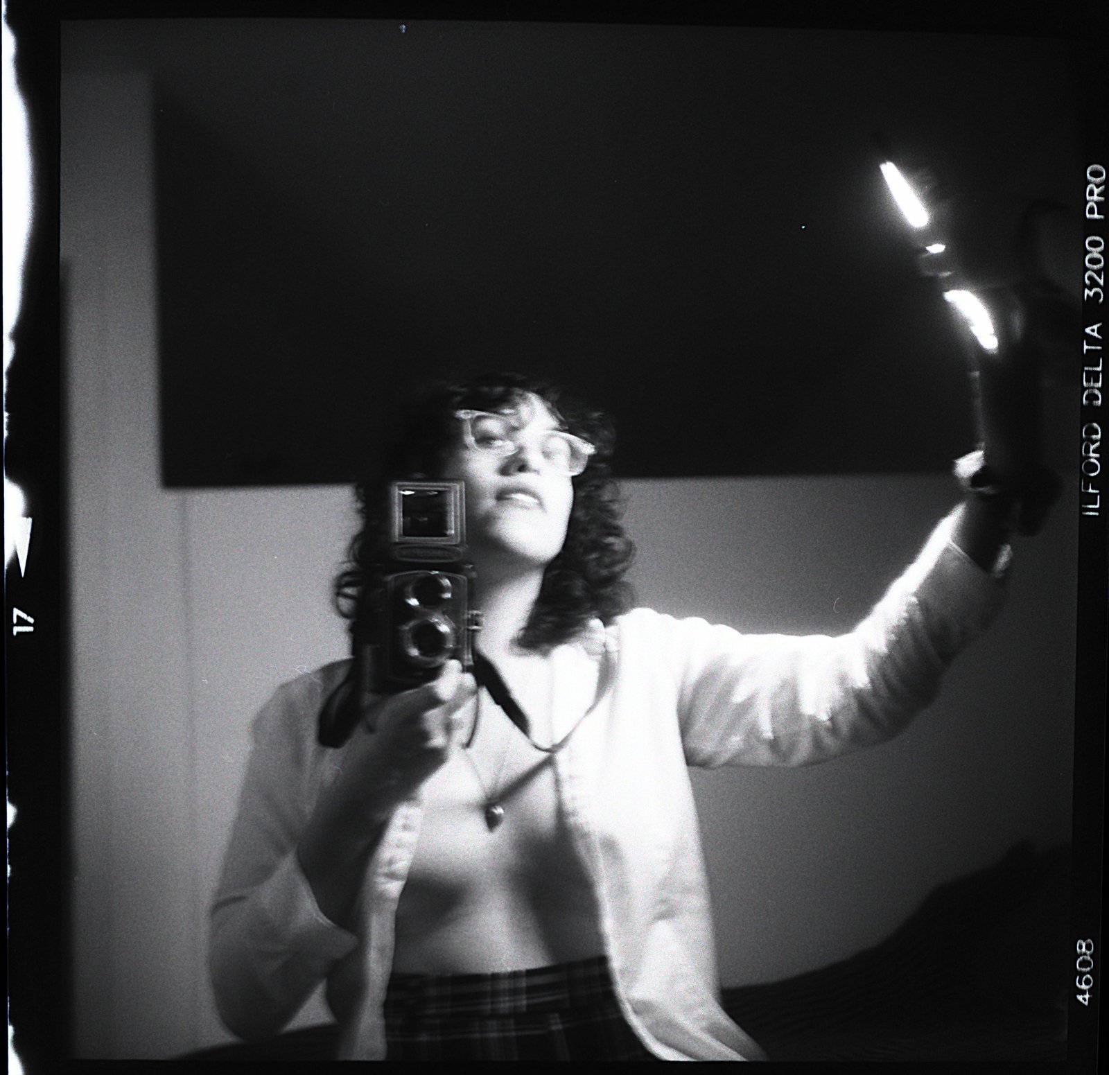 Arm reaching, camera in hand, light flaring overhead